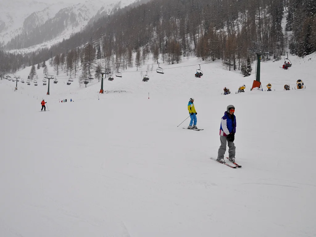 Blick über die Piste in ein nebliges Tal mit Sessellift.